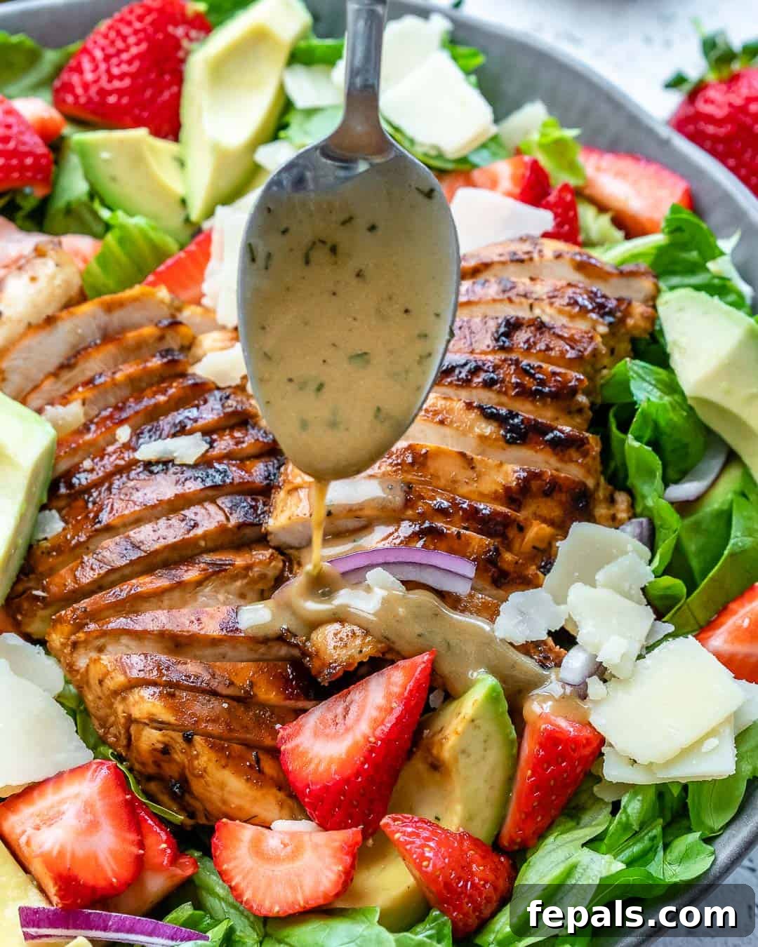 Vibrant Strawberry Chicken Salad 6 side view of salad with spoon drizzling mustard dressing over chicken