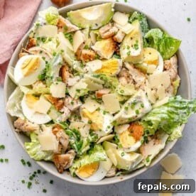 Caesar salad with chicken and boiled eggs in a round bowl.