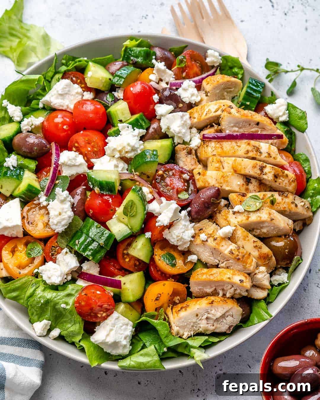 Zesty Mediterranean Chicken Salad 2 Top view of a colorful Greek Chicken Salad in a rustic bowl, showcasing fresh vegetables, grilled chicken, and crumbled feta cheese.
