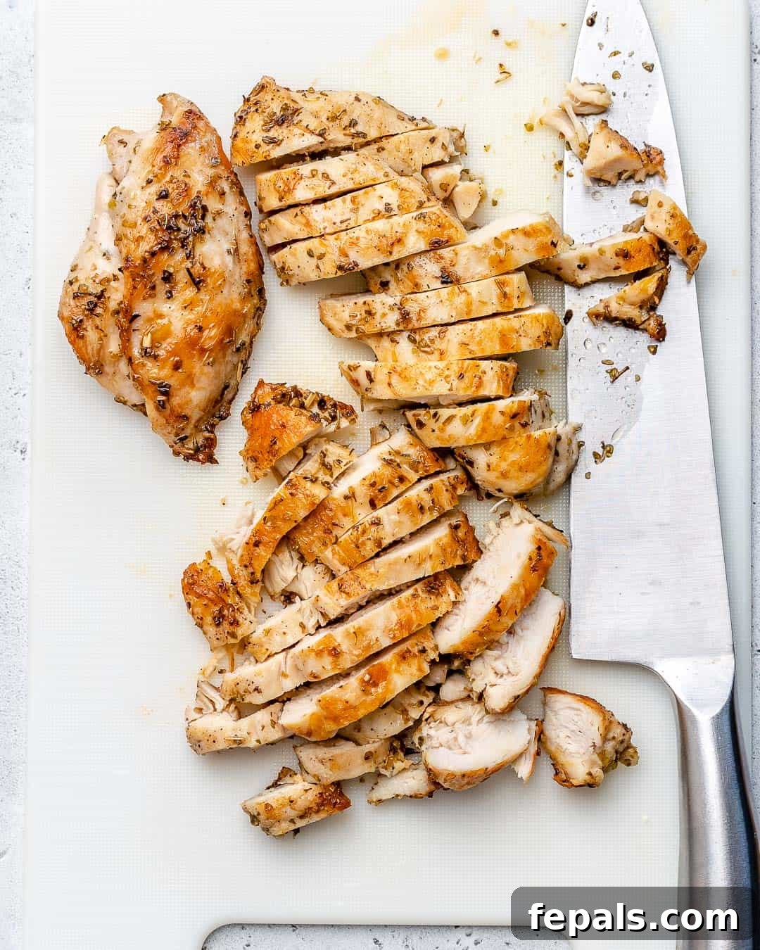 Zesty Mediterranean Chicken Salad 5 Perfectly sliced cooked chicken breast, golden-brown and juicy, arranged on a cutting board, ready to be added to the fresh Greek salad.