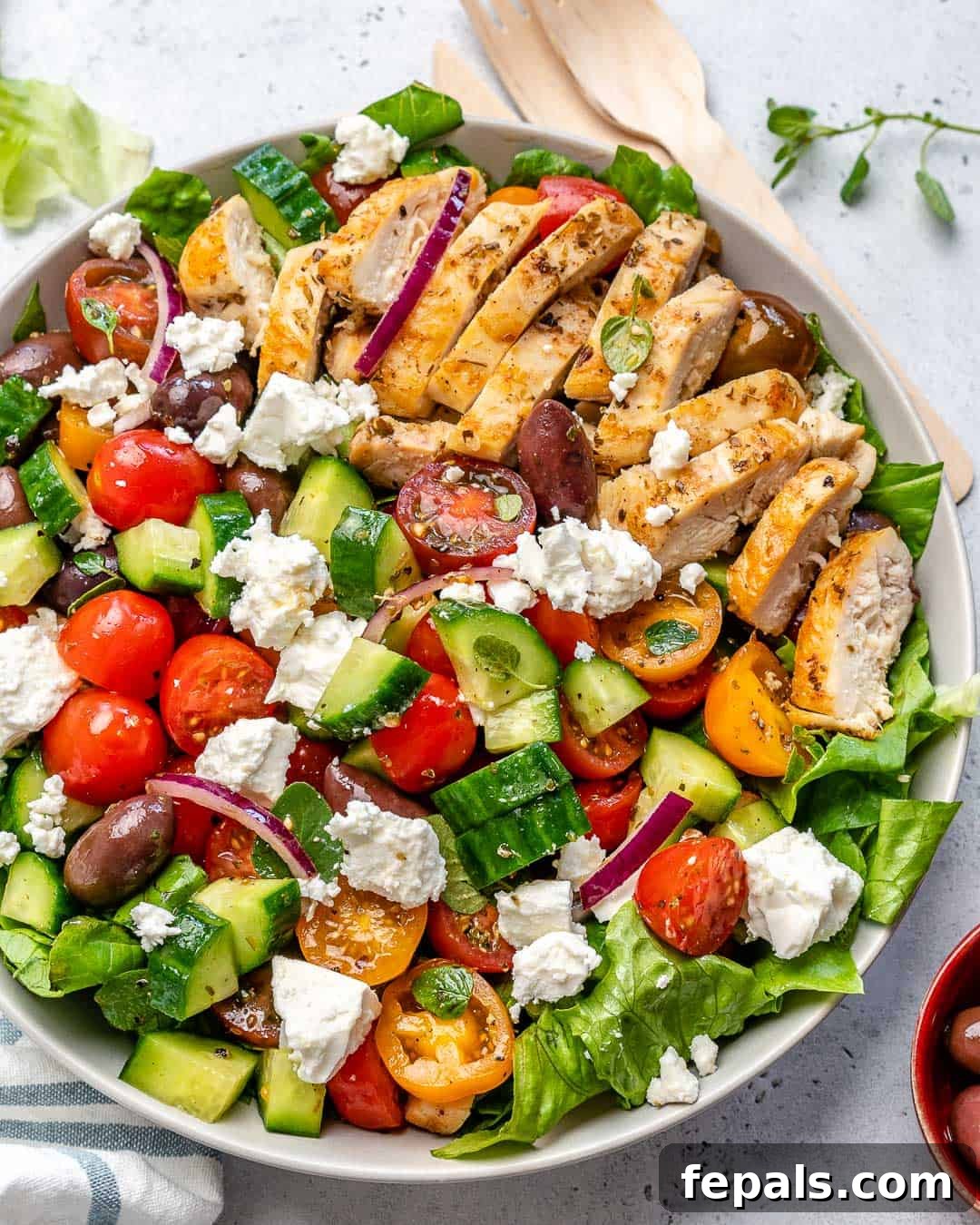 Zesty Mediterranean Chicken Salad 7 Grilled chicken slices beautifully arranged on a fresh Greek salad in a pristine white bowl, showcasing the perfect cook on the chicken.