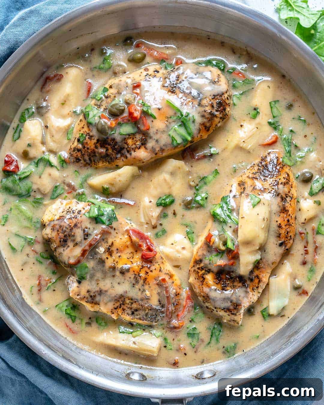 Creamy Tuscan Chicken Delight 2 Top view of creamy Tuscan chicken in a rustic skillet, garnished with fresh herbs, ready to be served for dinner.