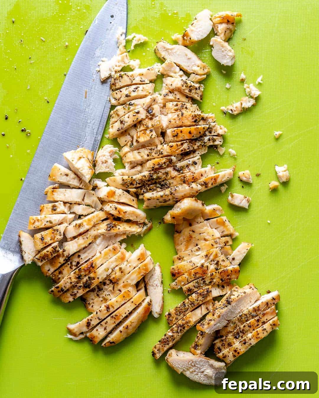 Perfectly cooked and sliced chicken breast arranged on a cutting board, ready to be added to the pasta salad.