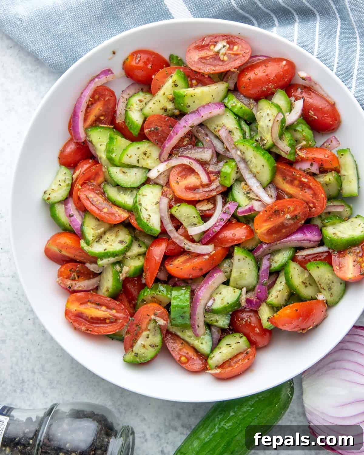 Summer's Delight Salad 2 Top view of a colorful cucumber and tomato salad in a pristine white bowl, showcasing the freshness of the ingredients.