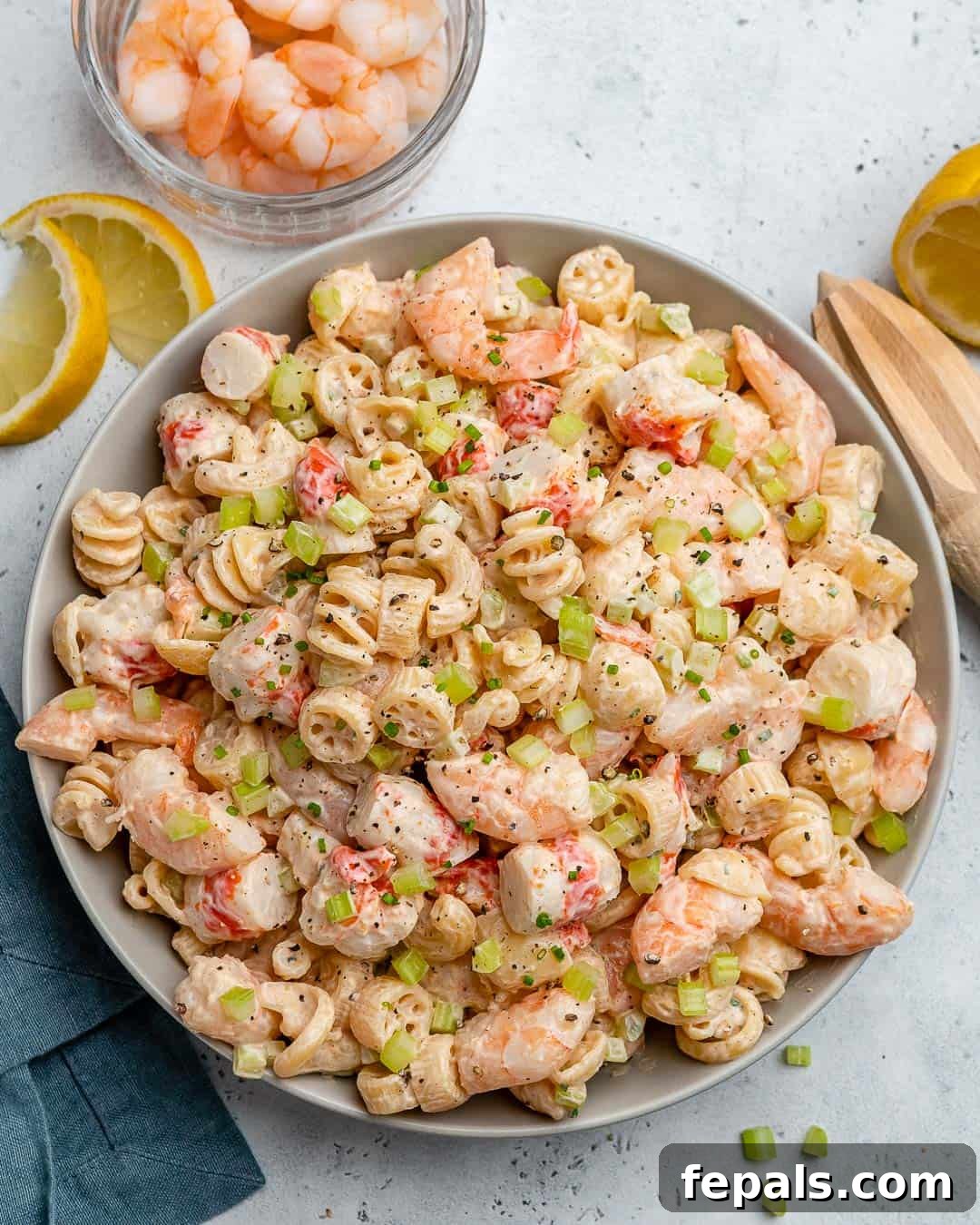 Top view of creamy shrimp pasta salad with fresh lemon slices as garnish