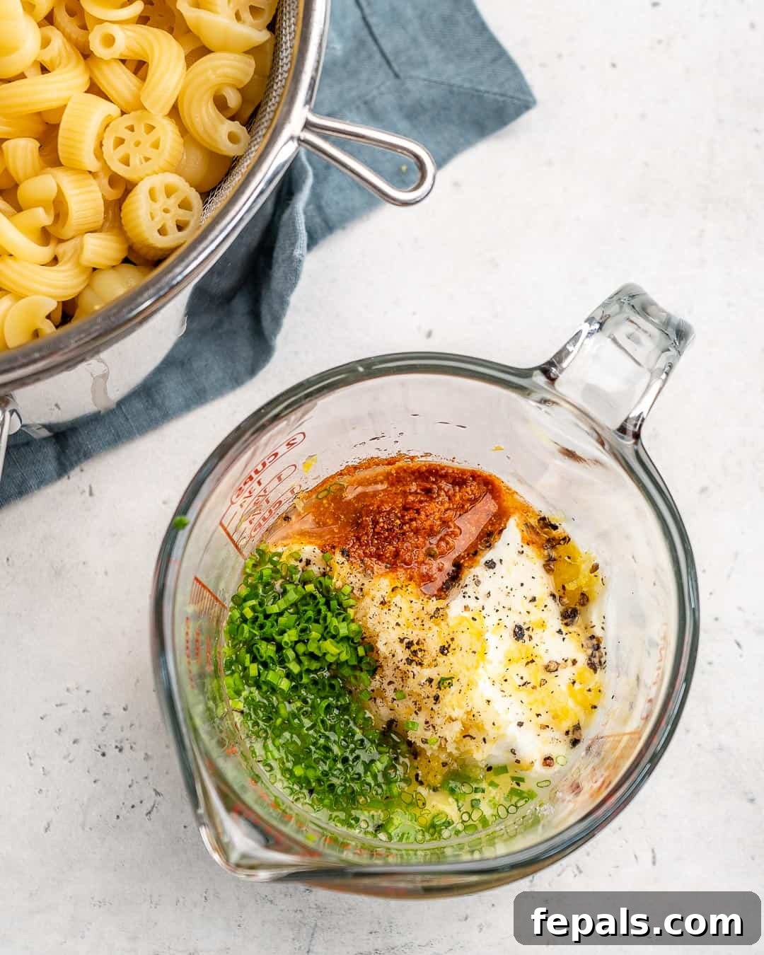 Creamy, zesty dressing for pasta salad being prepared in a bowl with a whisk, showing Greek yogurt, lemon, and spices