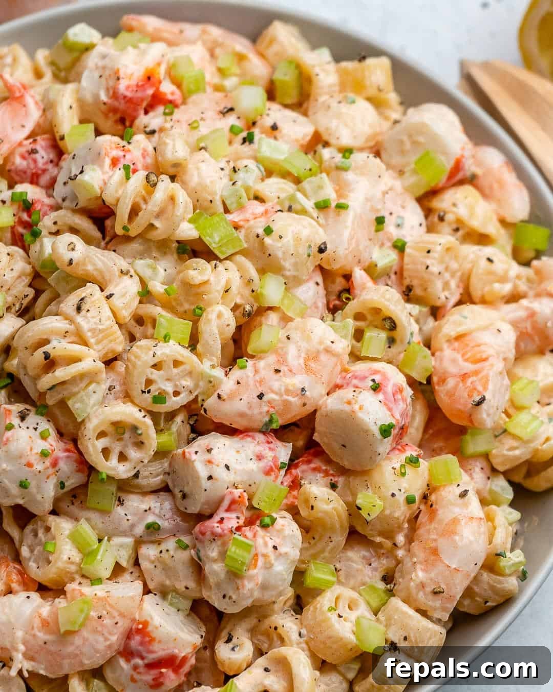 Close-up shot of a serving of creamy shrimp pasta salad in a white bowl, showing the texture and ingredients