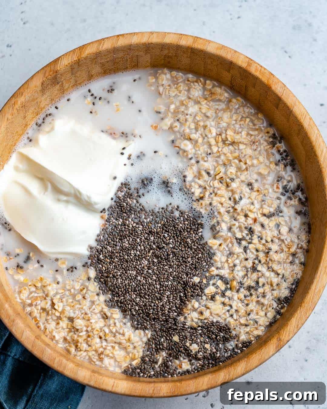 Effortless Greek Yogurt Overnight Oats 4 A round bowl containing oats, Greek yogurt, chia seeds, and other key ingredients, poised for mixing into delicious overnight oatmeal.