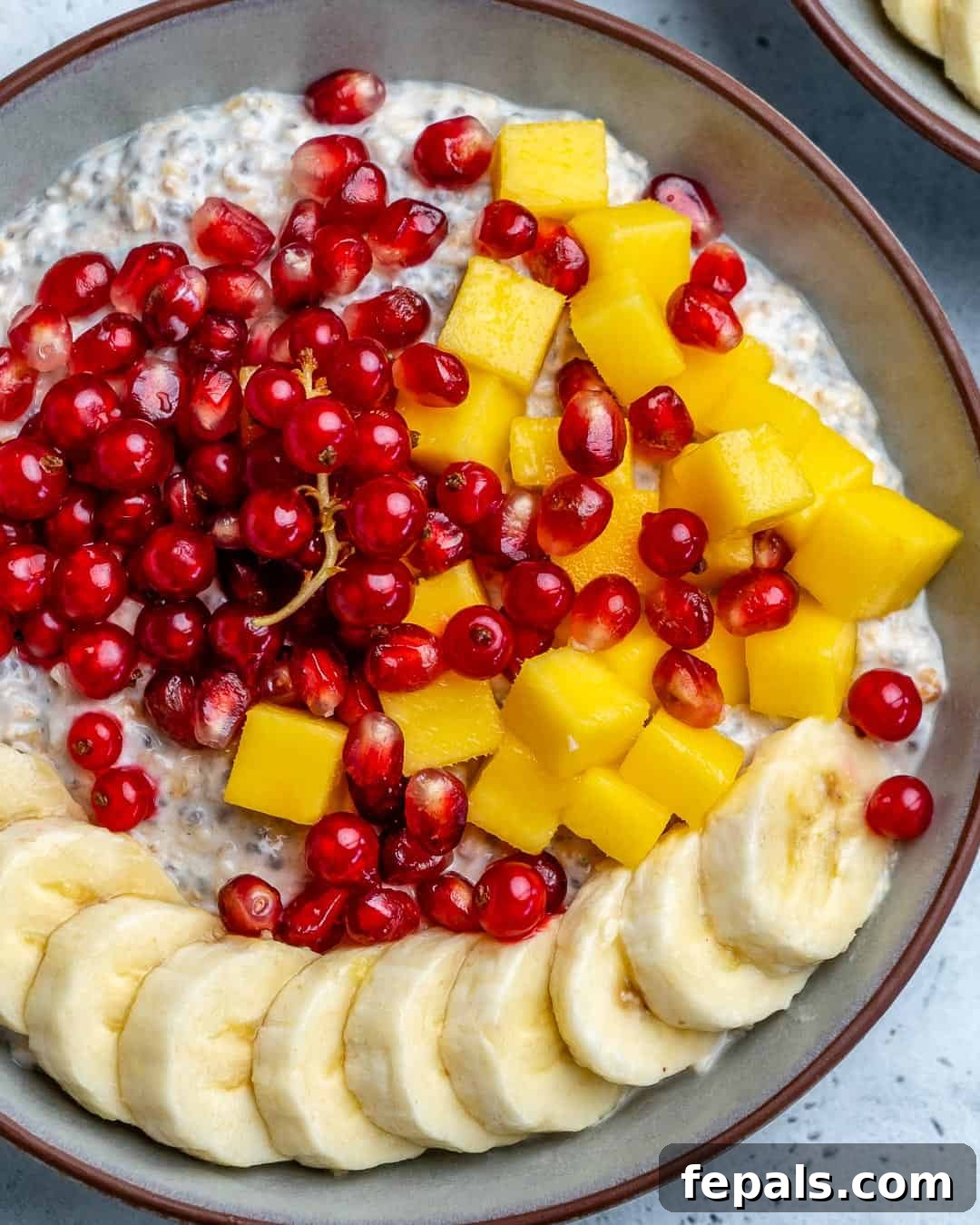 Effortless Greek Yogurt Overnight Oats 7 A charming round bowl of overnight oatmeal, elegantly garnished with a variety of fresh fruits, showcasing a delicious and healthy breakfast option.