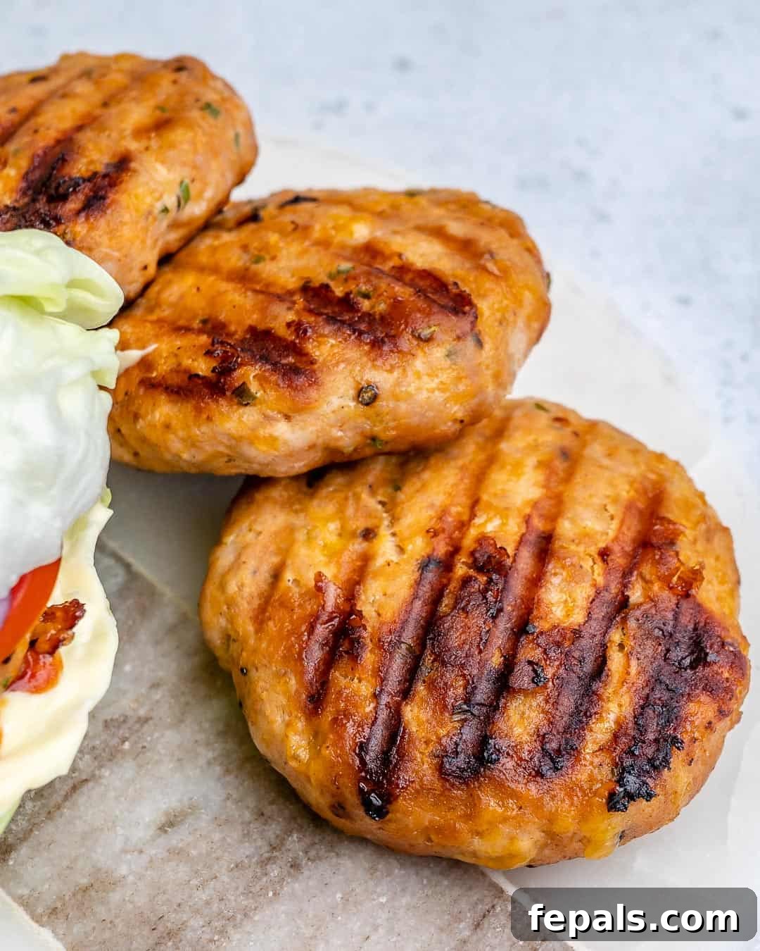 A beautifully presented platter of chicken burger patties, ready to be enjoyed with a variety of fresh toppings and sides.