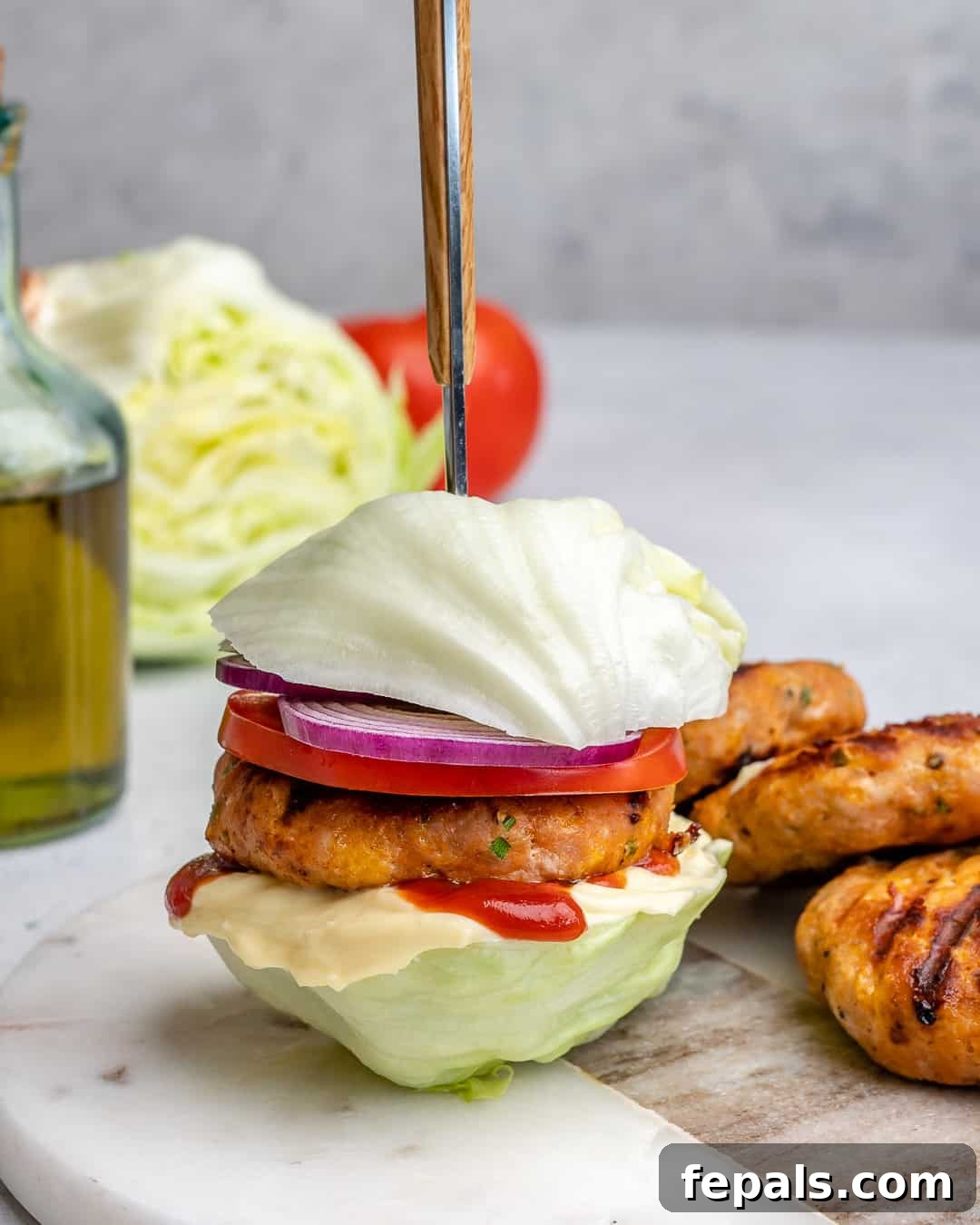 A pristine chicken burger served in a fresh lettuce bun, positioned artfully on a white platter, highlighting its healthy and appealing nature.
