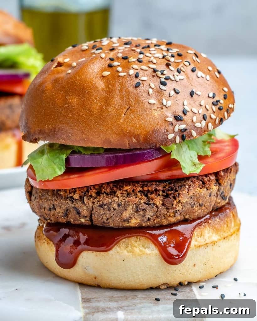 side shot of a vegan bean burger on a flat surface with bbq sauce dripping