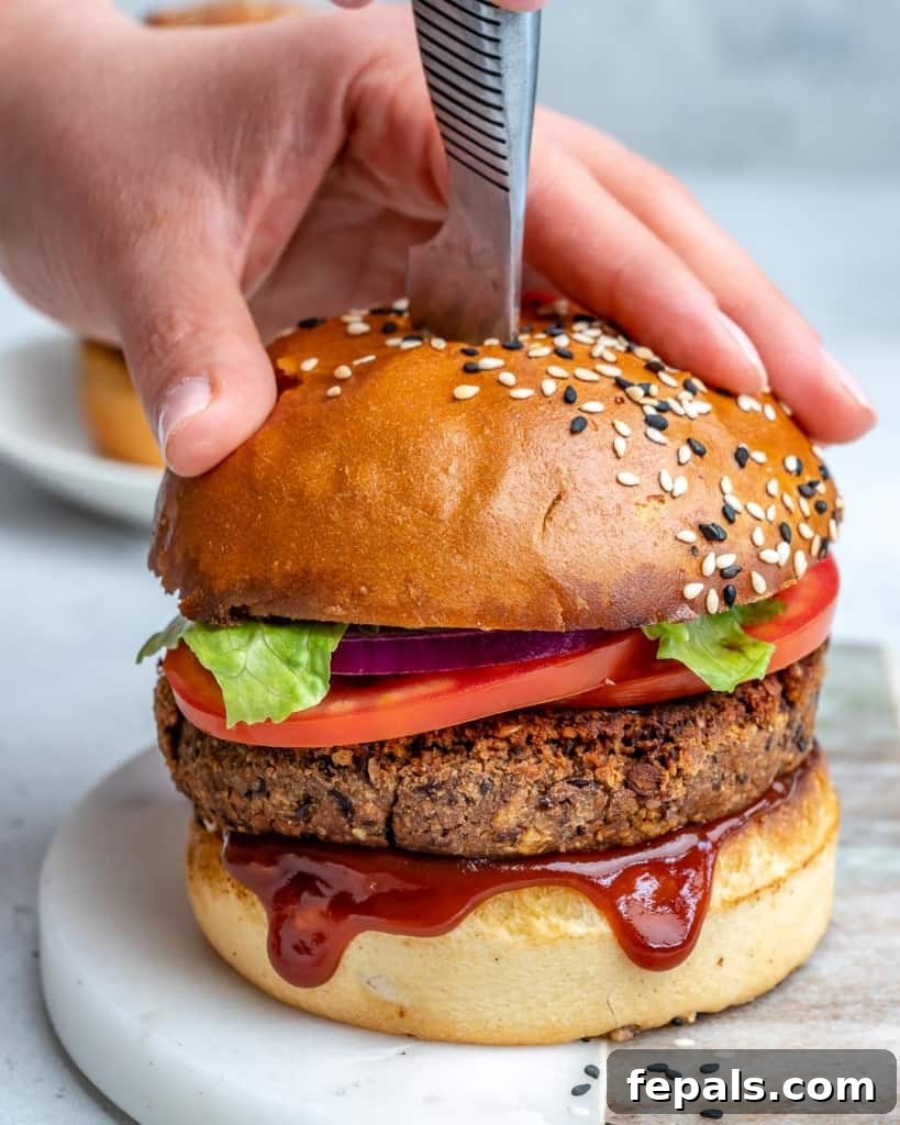 hand holding down a bean burger with knife placed in the middle of the burger