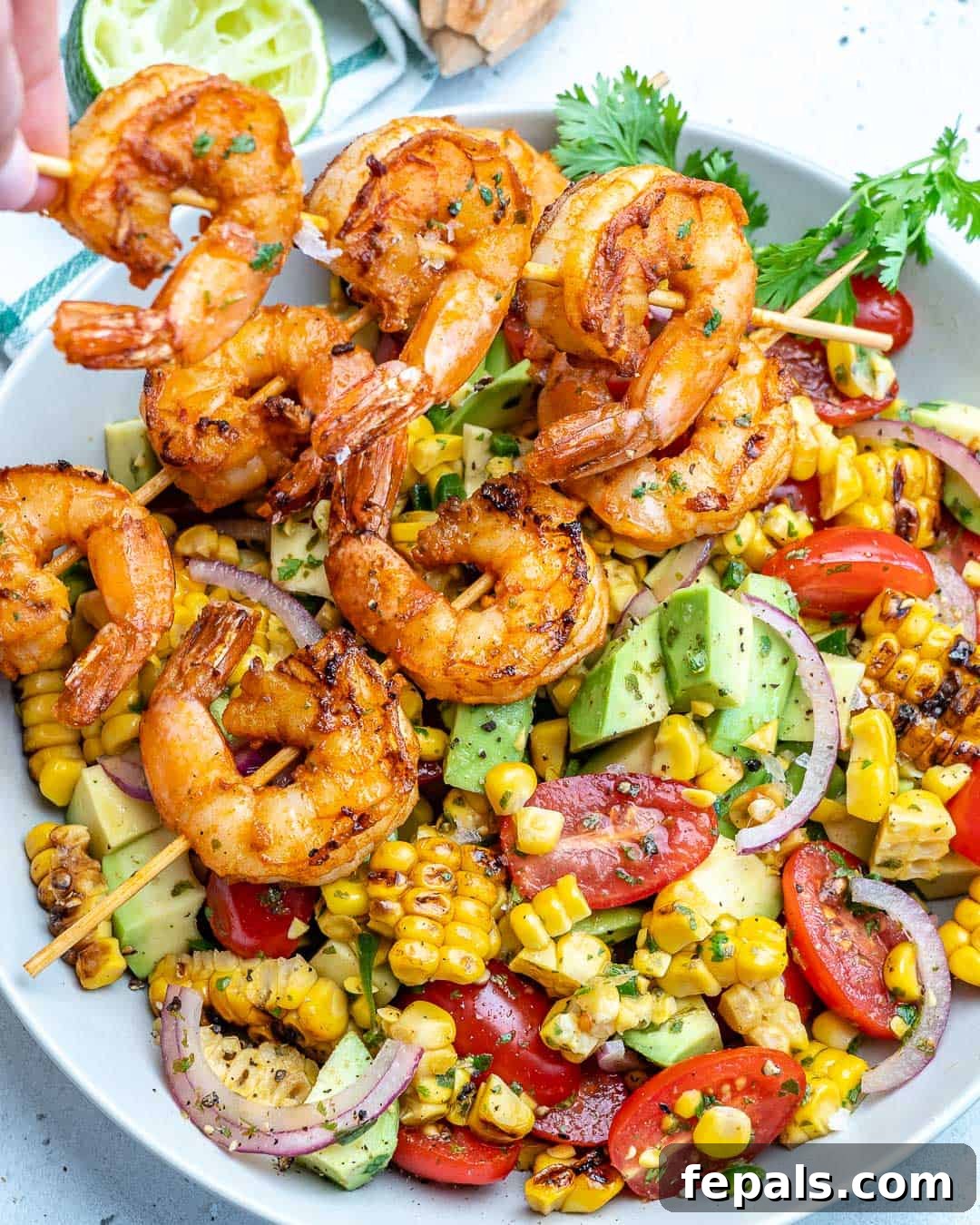 Zesty Shrimp Avocado Corn Salad 6 holding shrimp skewer over corn salad