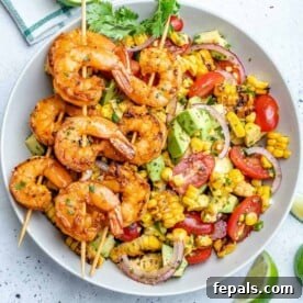 top view of corn salad with 3 skewers of grilled shrimp over salad
