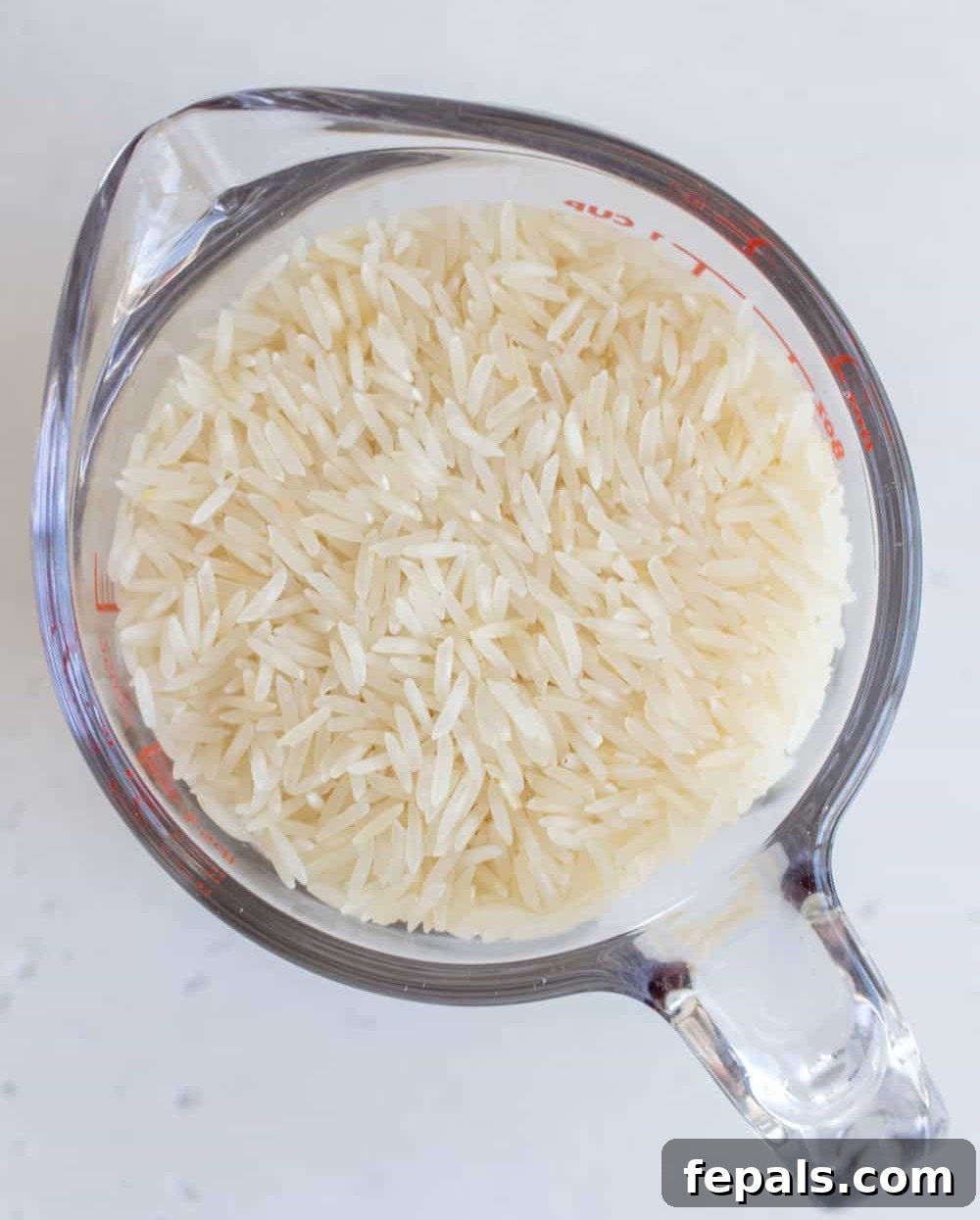 Perfectly Fluffy Rice Every Time 3 Raw basmati rice in a measuring cup, ready for cooking.