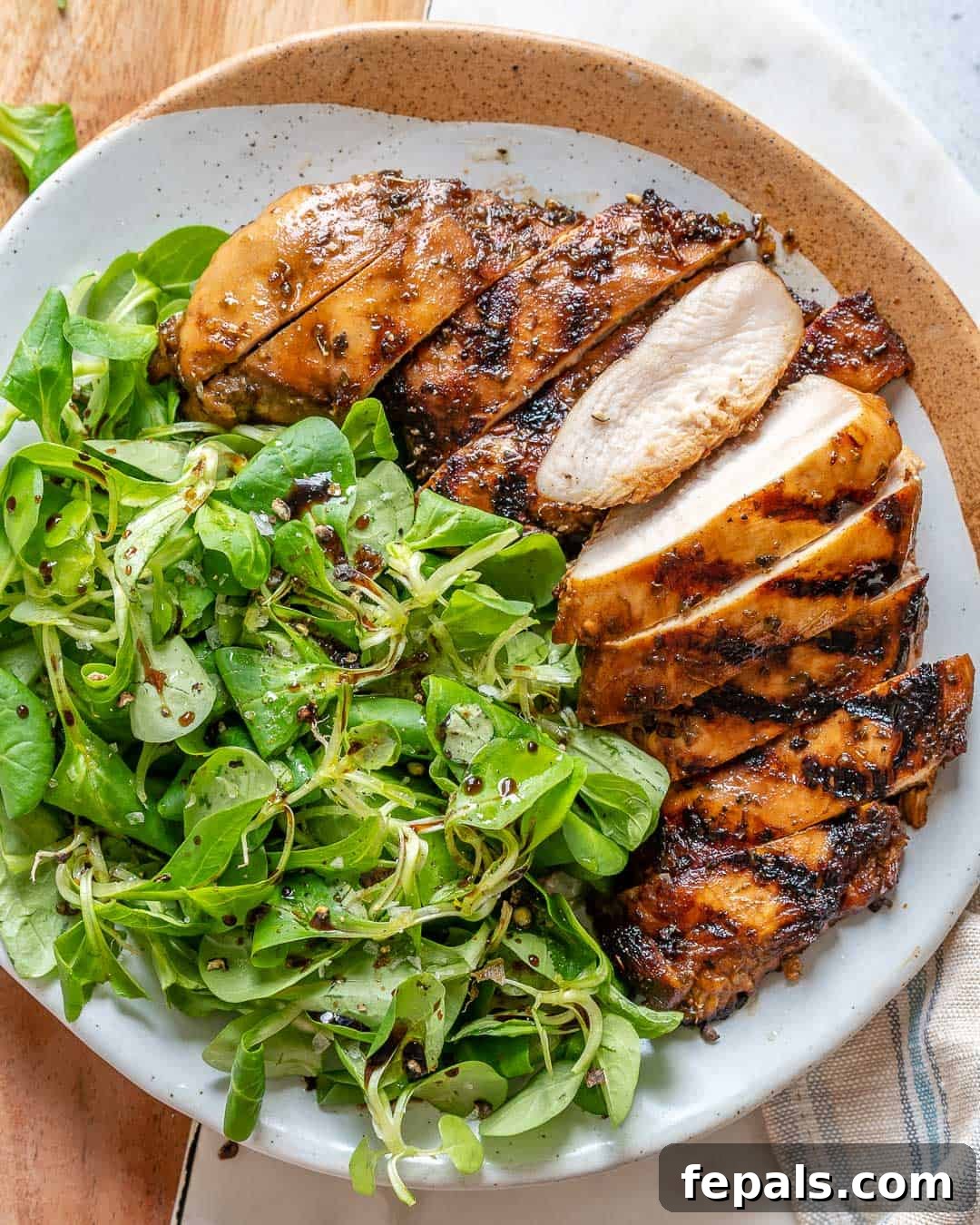 A succulent balsamic glazed chicken breast served alongside a fresh green salad, highlighting its crispy exterior and vibrant color.