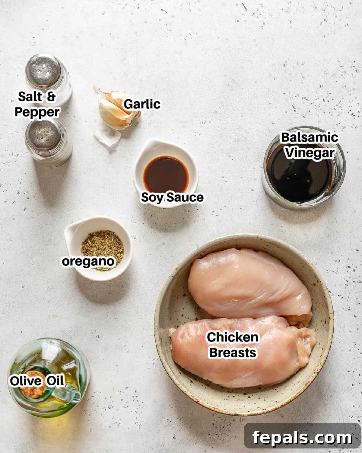 A vibrant flat lay of all fresh ingredients required to make delicious balsamic chicken, including chicken breasts, olive oil, balsamic vinegar, garlic, and dried oregano.