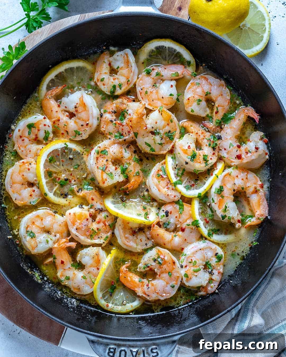 top view of shrimp in skillet, garnished with fresh parsley and lemon slices