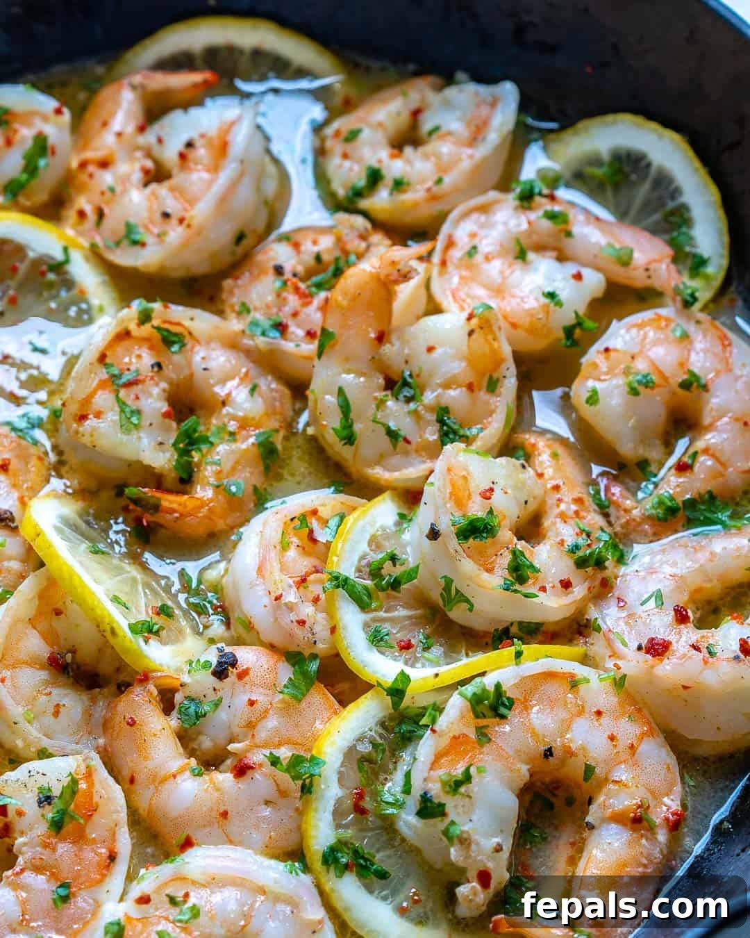 sauteed shrimps in skillet with lemon slices
