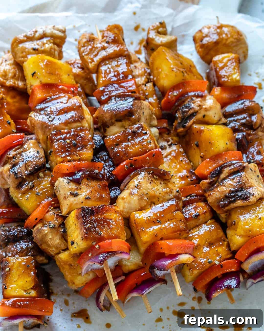 Sweet and Savory Pineapple Chicken Skewers 3 grilled chicken skewers on a parchment paper