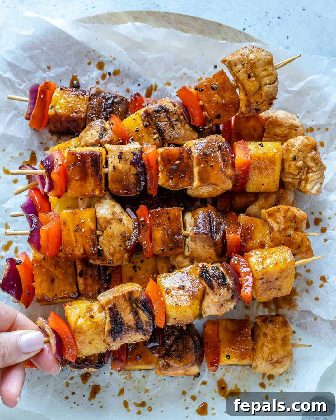 Sweet and Savory Pineapple Chicken Skewers 8 hand holding one grilled chicken kabob