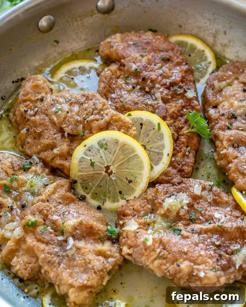 close up of chicken francese with fresh lemon slices and parsley garnish