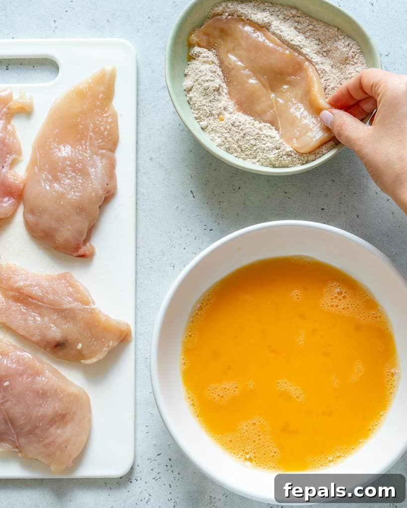 chicken being dipped in flour mixture for coating
