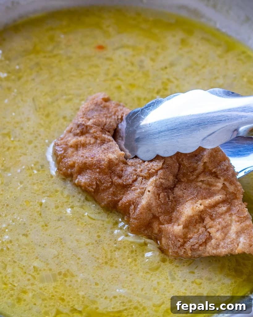 fried chicken being placed back into the skillet with the lemon sauce
