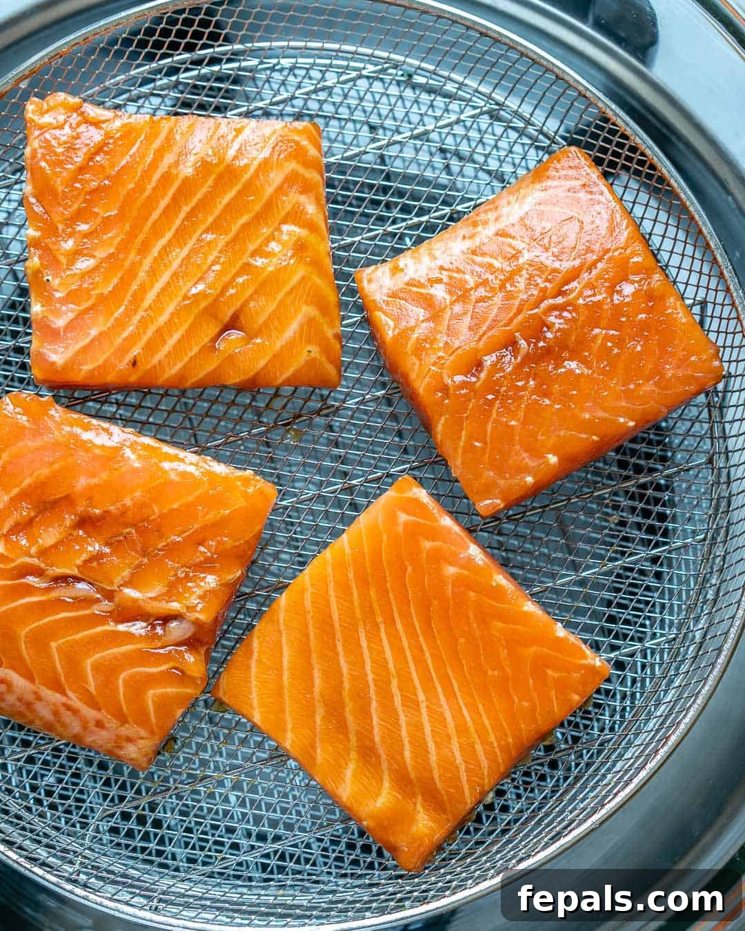 Airfryer'da Nar Gibi Kızarmış Ballı Somon 6 Carefully placing salmon fillets skin-side down into the air fryer basket for even cooking.
