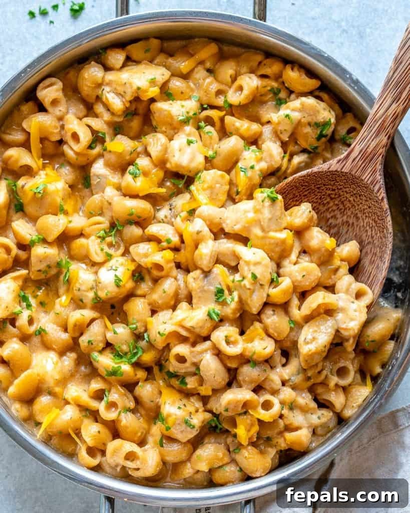 Spicy Buffalo Chicken Macaroni Bake 2 Creamy buffalo chicken mac and cheese with a wooden spoon in a cast iron skillet, ready to serve.