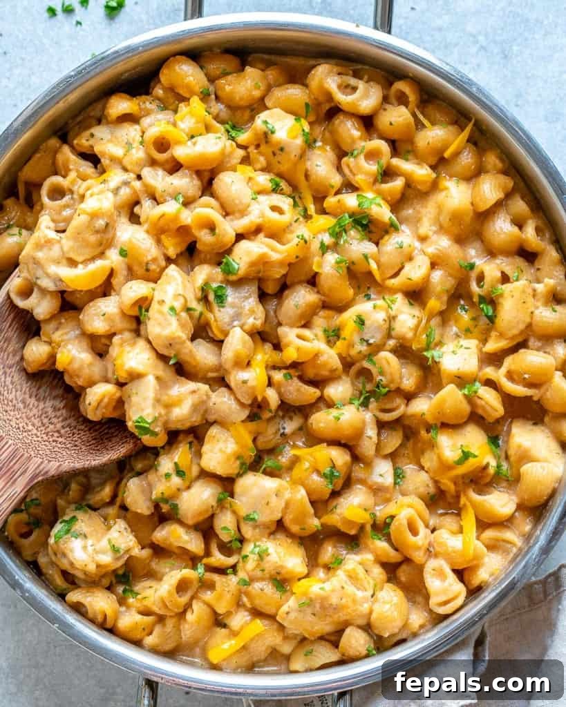 Spicy Buffalo Chicken Macaroni Bake 8 Top view of buffalo chicken mac and cheese in a skillet with a wooden spoon, garnished with fresh parsley.