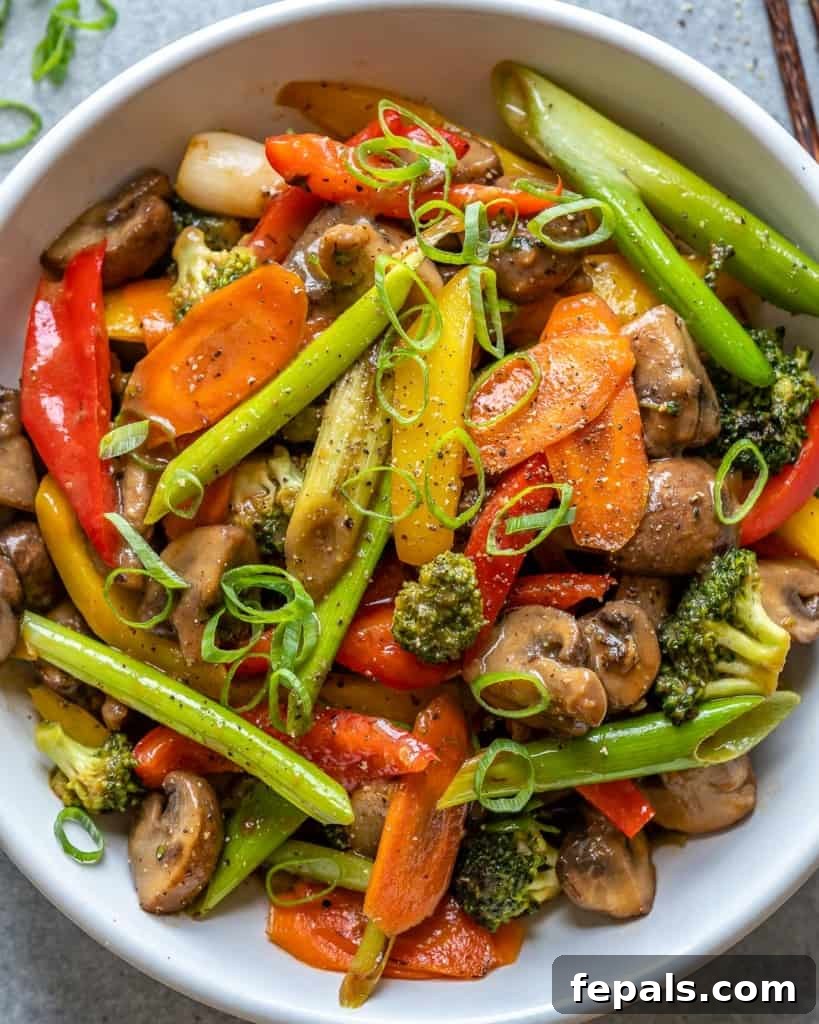 Vibrant Sweet and Sour Vegetable Stir-Fry 3 Overhead view of a vibrant vegetable stir fry in a white bowl with a spoon.