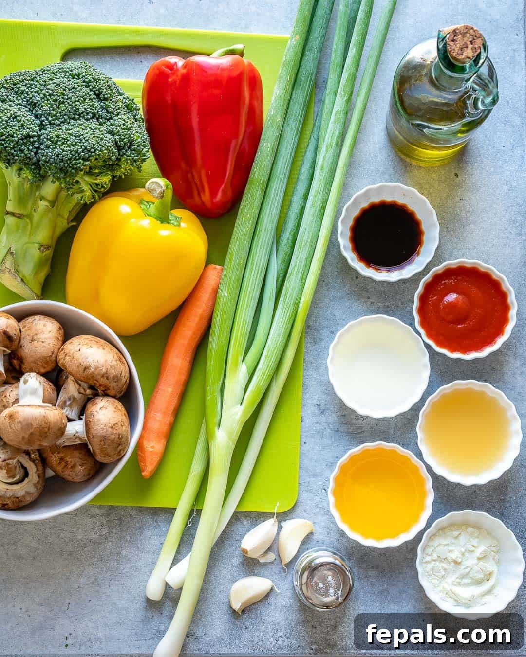 Vibrant Sweet and Sour Vegetable Stir-Fry 4 Raw ingredients for sweet and sour vegetable stir fry laid out on a kitchen counter, including fresh vegetables and sauce components.