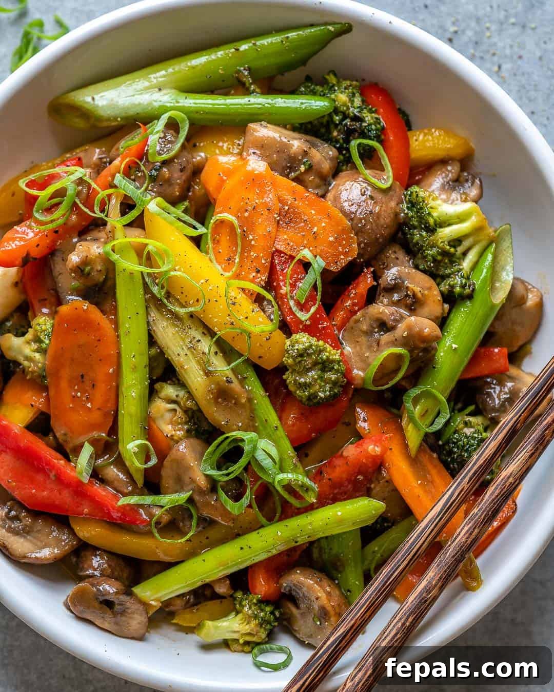 Vibrant Sweet and Sour Vegetable Stir-Fry 10 A white bowl of colorful vegetable stir fry with a pair of chopsticks resting on the side.