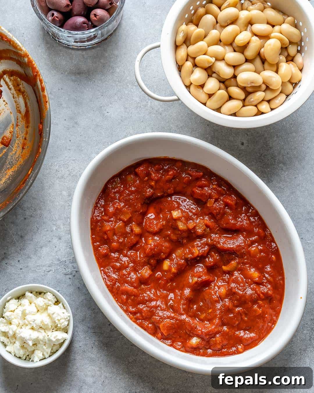 Gigantes Plaki 5 A close-up view of the tomato sauce for Greek Baked Beans simmering in a pan with herbs and spices.