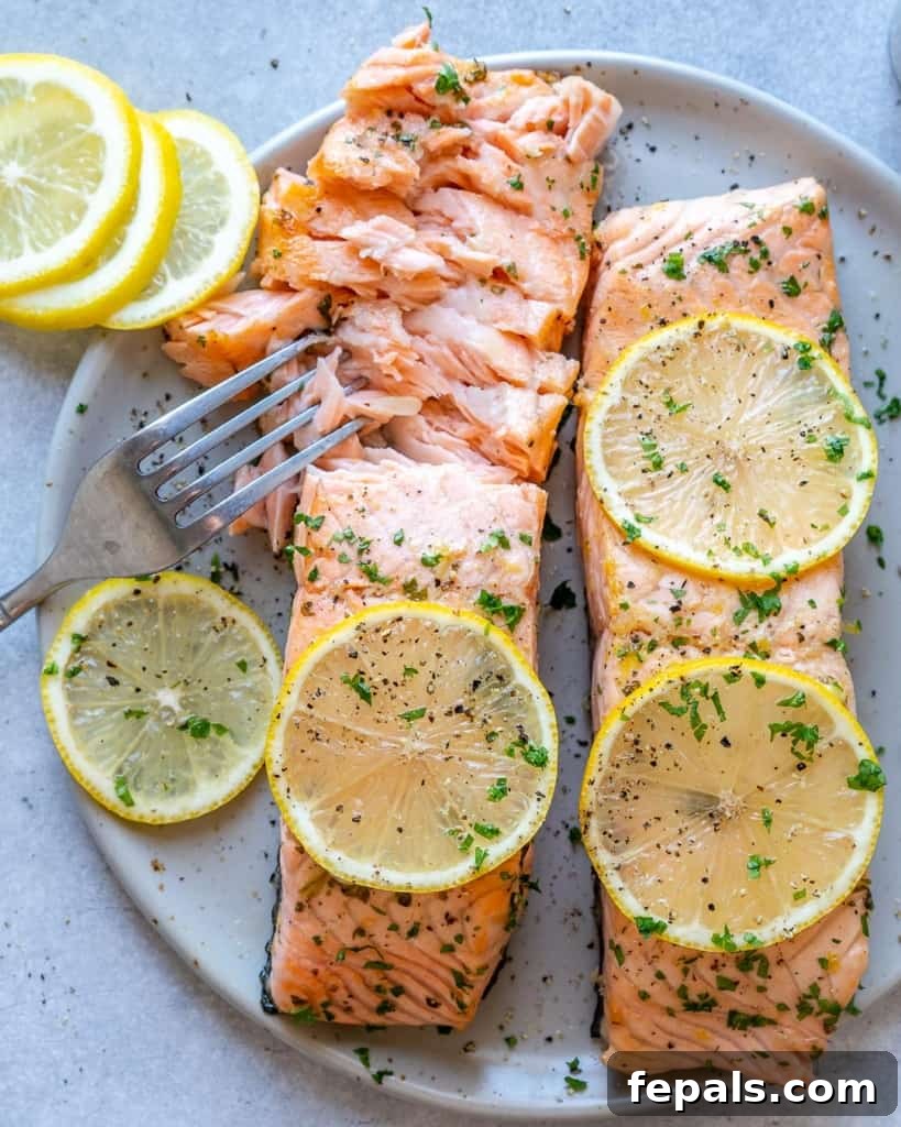 top view of fork flaking baked salmon on a white plate