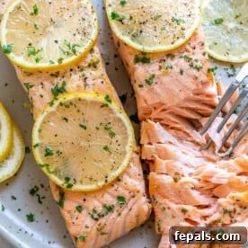 two baked salmon on plate with fork flaking it
