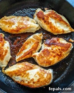 Several golden-brown cooked chicken breasts in a skillet.