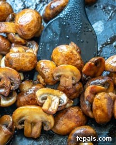Cooked sliced mushrooms in a skillet, lightly browned.