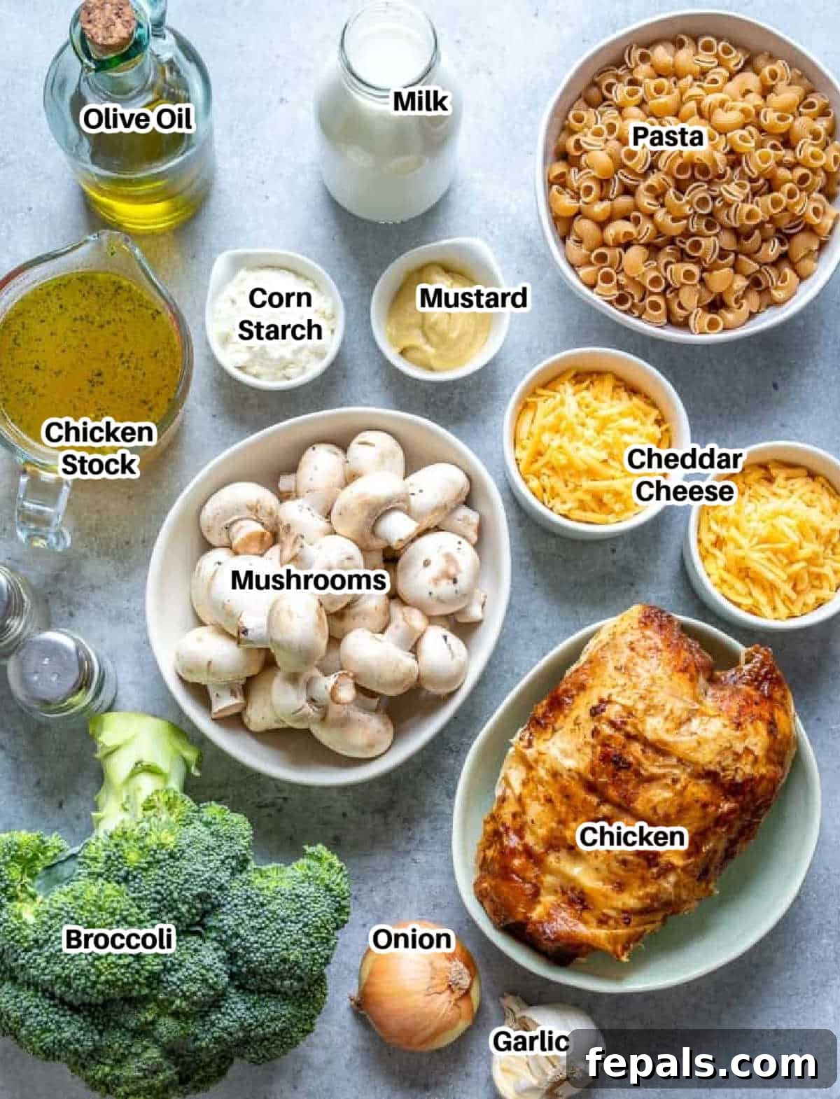 Various fresh ingredients laid out on a wooden board, including broccoli, mushrooms, onions, and cheese, essential for making the chicken pasta and broccoli casserole.