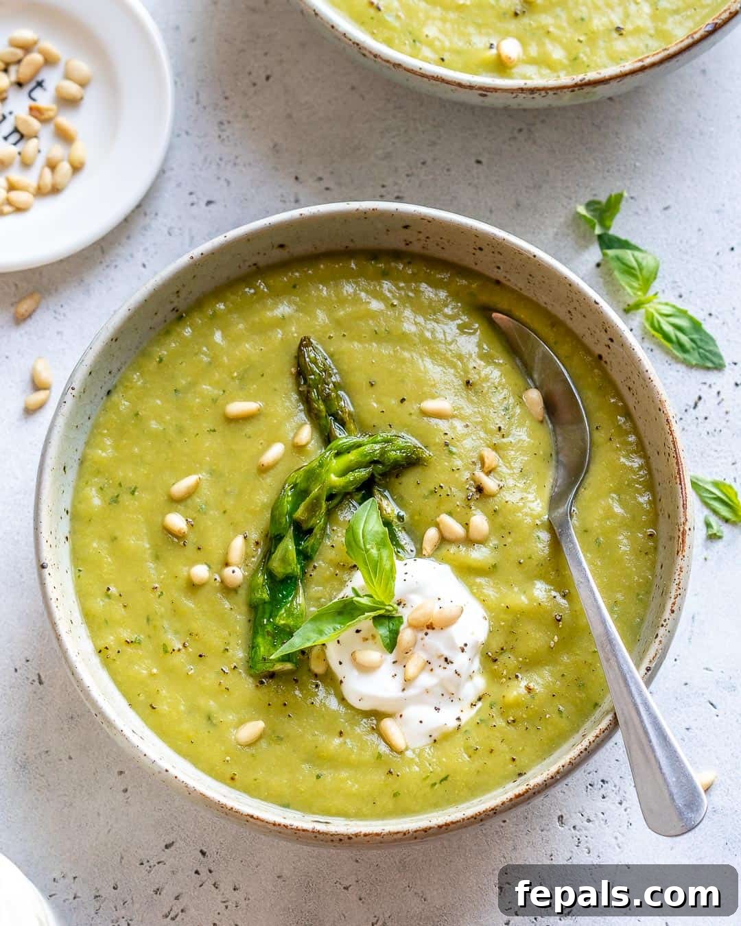 Velvet Asparagus Soup 2 Bowl of asparagus soup garnished with yogurt, basil, and pine leaves