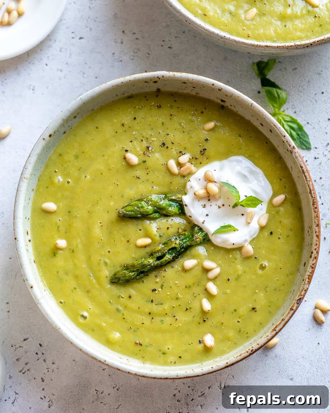 Velvet Asparagus Soup 8 Bowl of Health Asparagus Soup garnished with yogurt, pine nuts, and basil.
