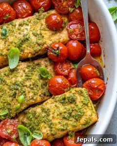 Spoon scooping cherry tomatoes and salmon out of white dish