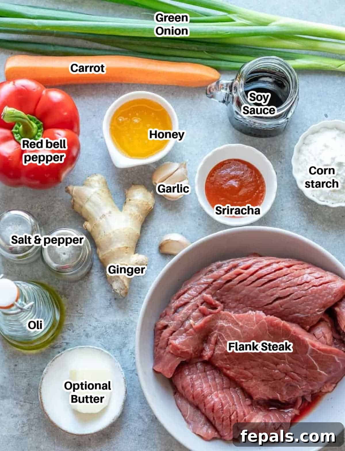 A colorful array of fresh ingredients for Mongolian beef, including sliced beef, carrots, bell peppers, green onions, and sauce components.