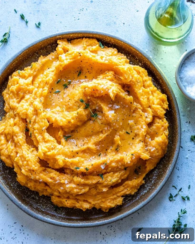 Velvety Sweet Potato Mash 2 A rustic brown bowl filled with perfectly smooth, mashed sweet potatoes, garnished lightly. This image highlights the creamy texture and inviting warmth of the dish.