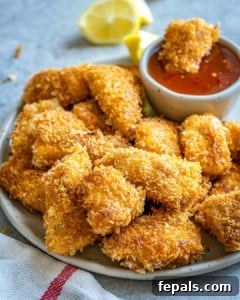Crispy Air Fryer Chicken Nuggets 10 Air fryer chicken nuggets piled on plate with bowl of ketchup