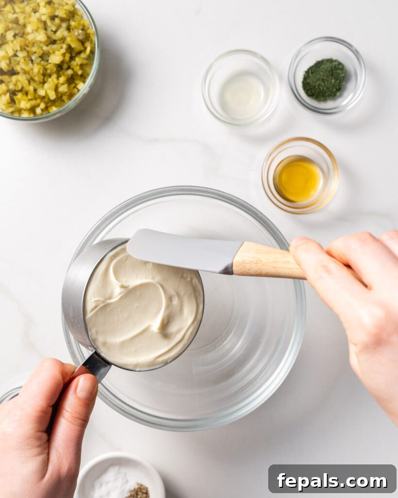 spatula removing mayo from measuring cup into the bowl