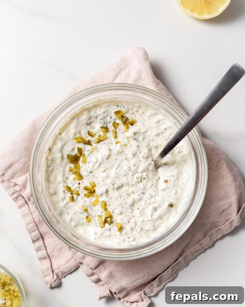 spoon in a bowl of tartar  sauce with dill relish over it 