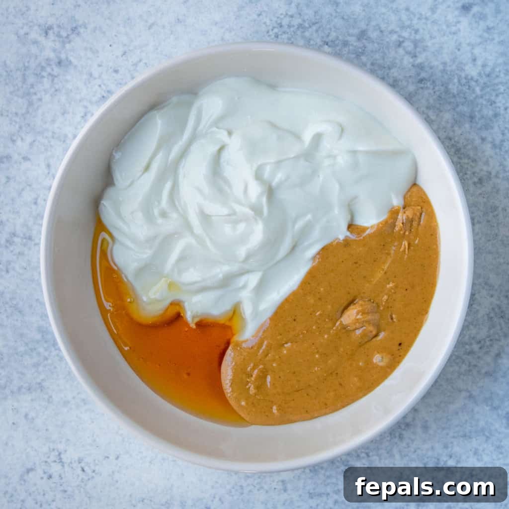 Peanut Butter Bliss Dip 9 3 ingredients, yogurt, honey, and peanut butter in white bowl